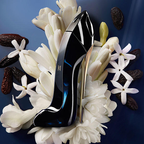 Carolina Herrera Good Girl kvepalai tarp gėlių tamsiame fone – Aromatale.lt